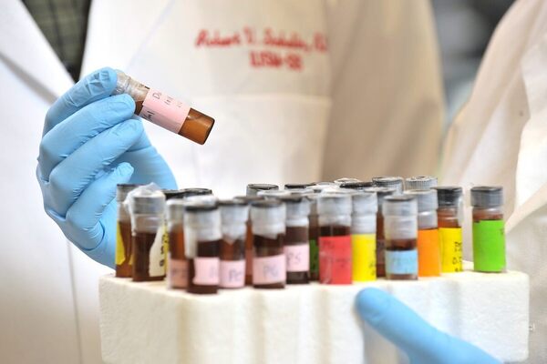 A medical student holds a tray of colorful vials