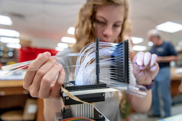 A student manipulates equipment with numerous fibers in the QuarkNet Center