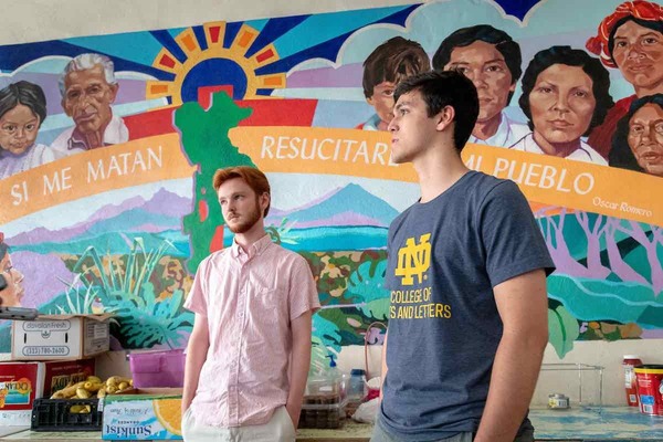 Students stand in front of mural for the Center for Social Concerns