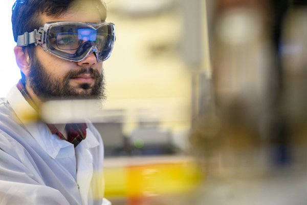 Student wearing heavy duty goggles works in a research lab