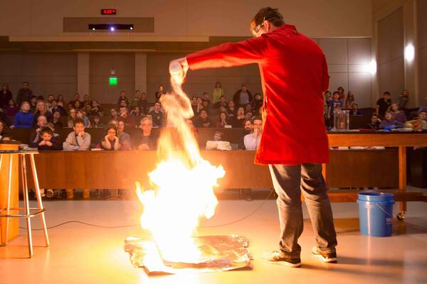 Presenter conducts experiment that produces a large flame at an Our Universe Revealed talk
