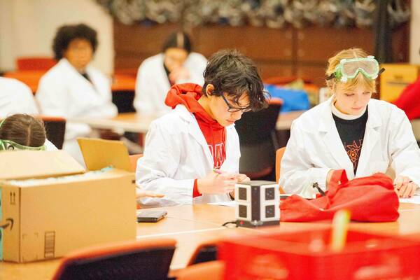 Science Olympiad 2023: High school students wearing lab coats complete challenges