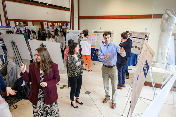 Crowded poster session with students presenting their research