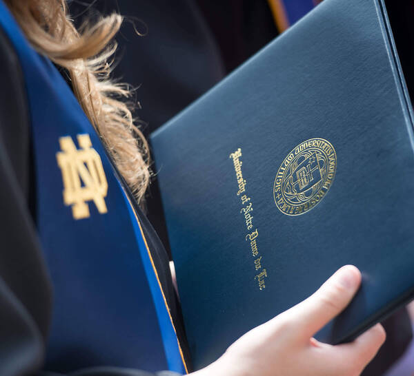 Graduating student holds a diploma.